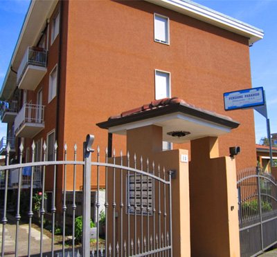 L'ingresso della pensione: palazzina in mattoni, cancello in ferro e insegna blu Pensione Paradiso